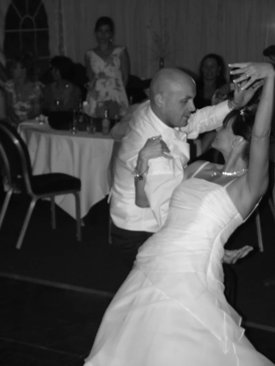 two brides and one groom dancing in front of people