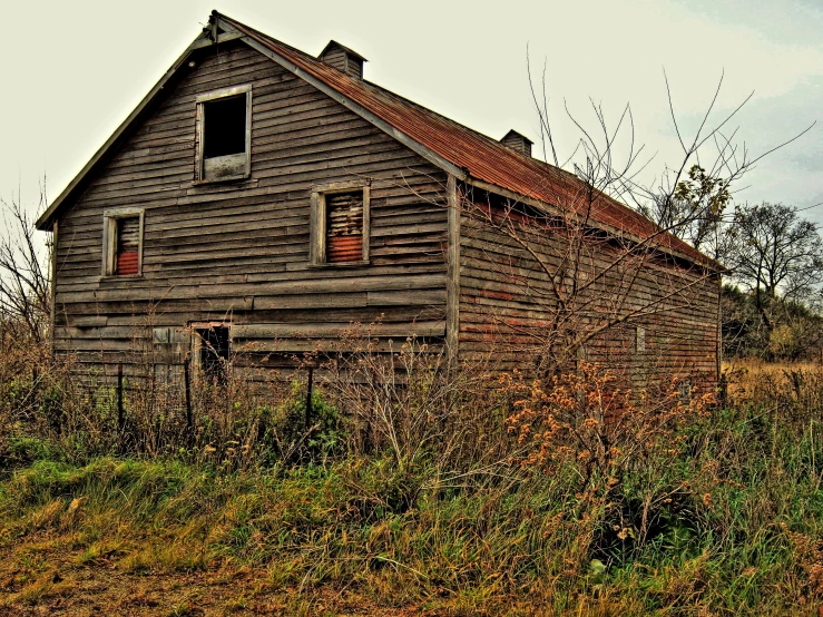 an old, weathered building sits in the middle of a field