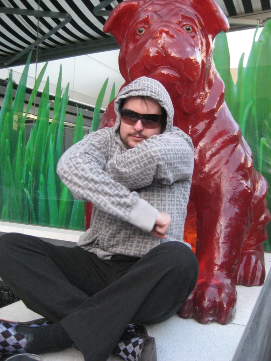 a guy sitting on a ledge next to a red bear