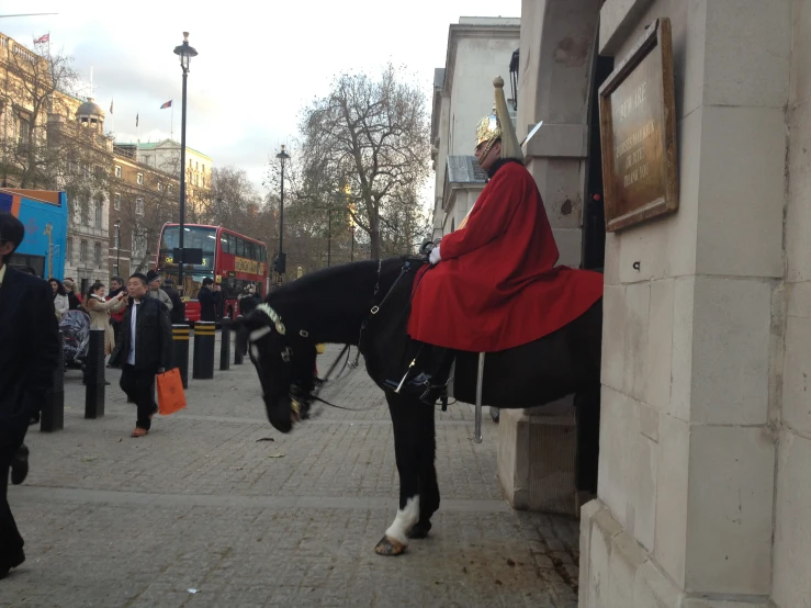 a man wearing a red robe sitting on a black horse