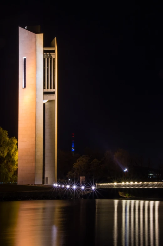 tall clock tower at night with reflecting water