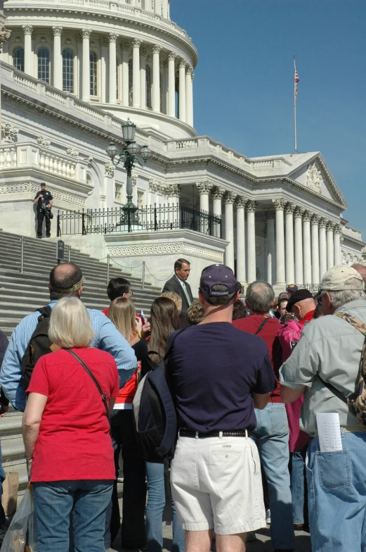 people gather on steps to look at the white house