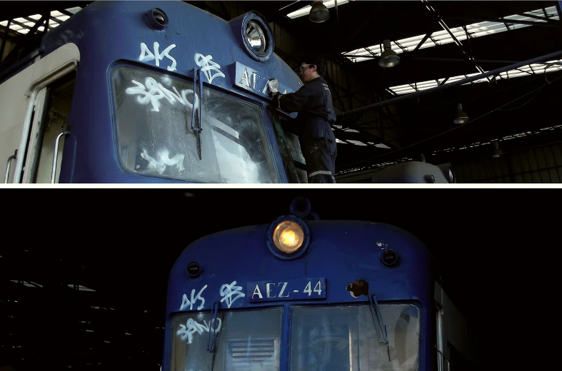 a blue train with graffiti on it is seen at night