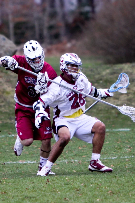 two young men playing a game of lacrosse on a field