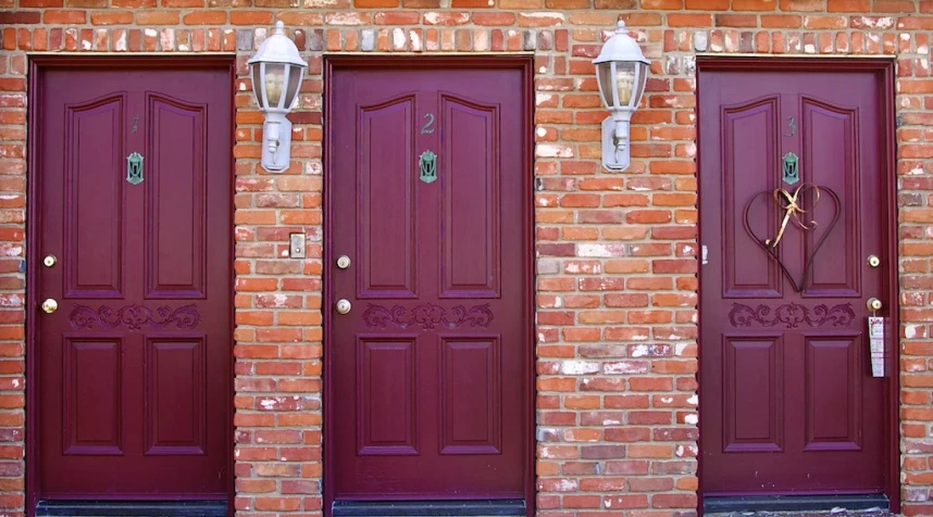 three red doors and two lights on a brick wall