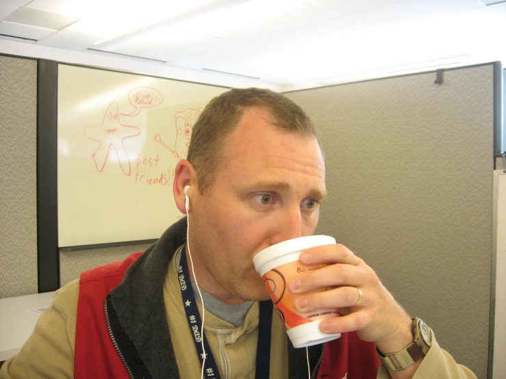man with white cup on his left hand drinking soing