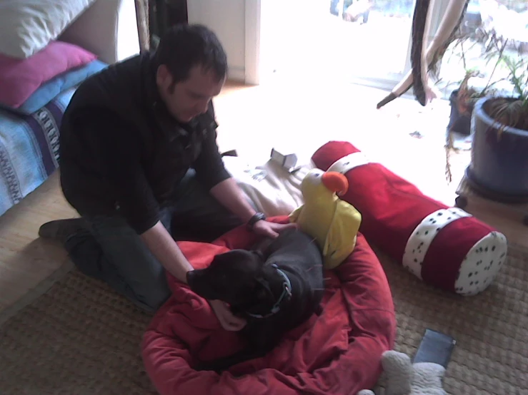 a man petting his dog as another sits on the floor