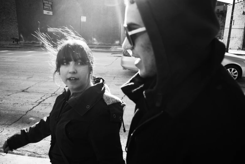 two girls standing on a sidewalk in black and white