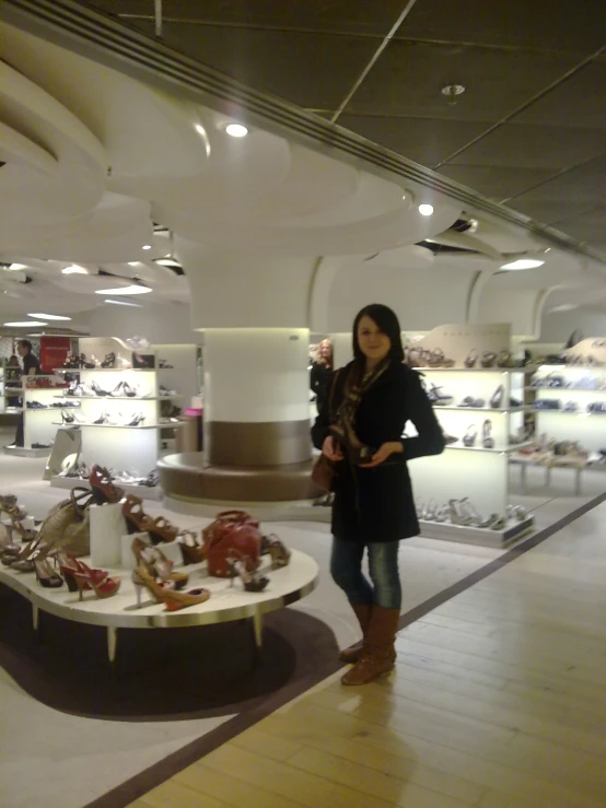 a women standing next to a table filled with lots of shoes