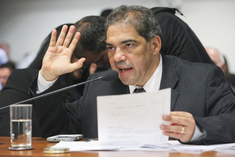 a man speaking at a podium with his hands outstretched