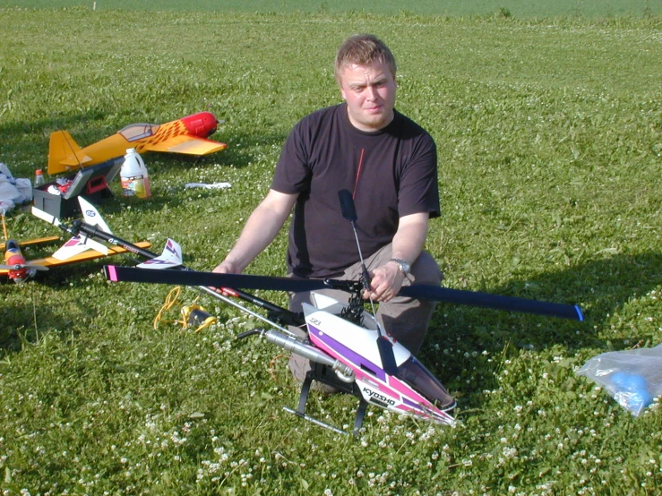 a man sitting on top of the grass holding a kite