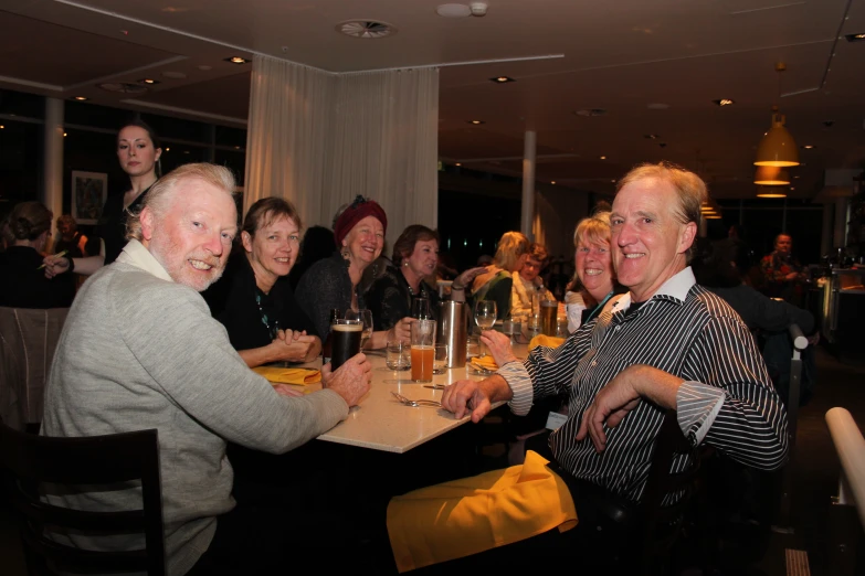 many people smiling and sitting at the table