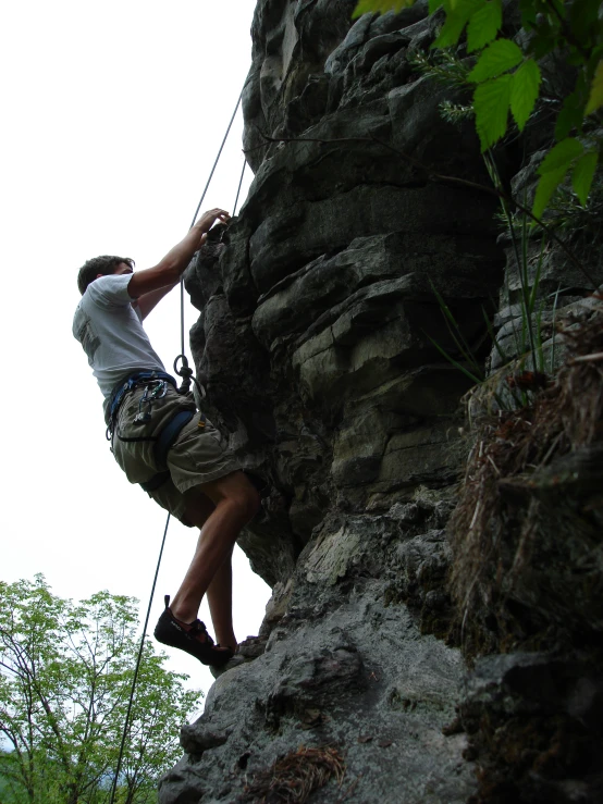 an image of man holding onto the rope of rock wall