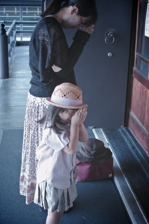 a little girl in a hat is standing by the door