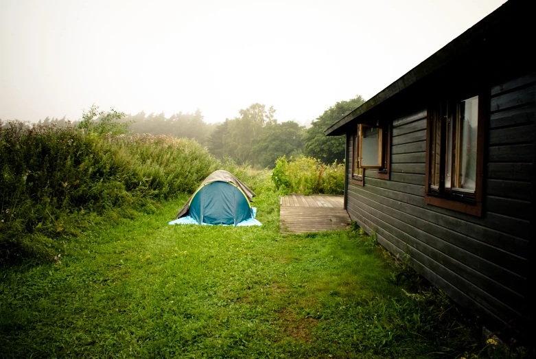 a small house with a tent next to it in the grass