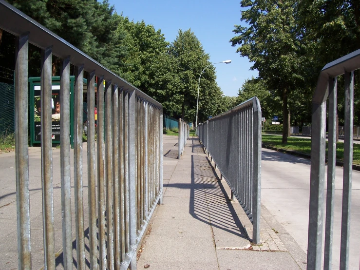 fenced area beside a walkway with green trees