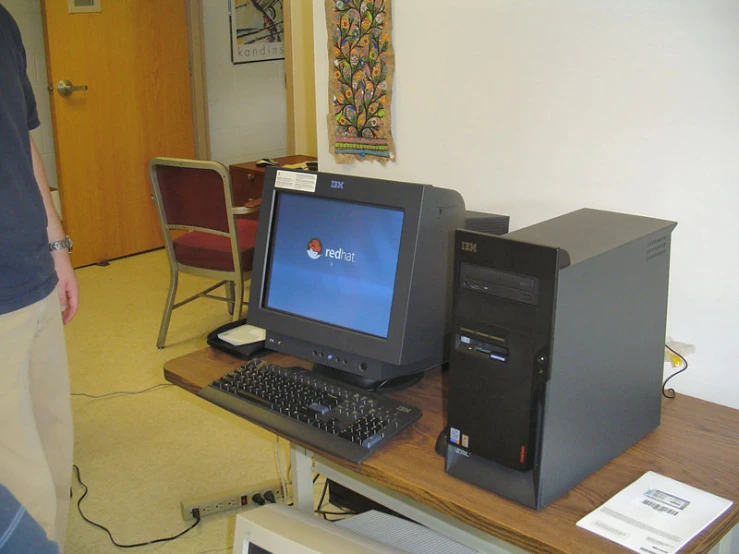 a man standing next to a desk with a monitor on it