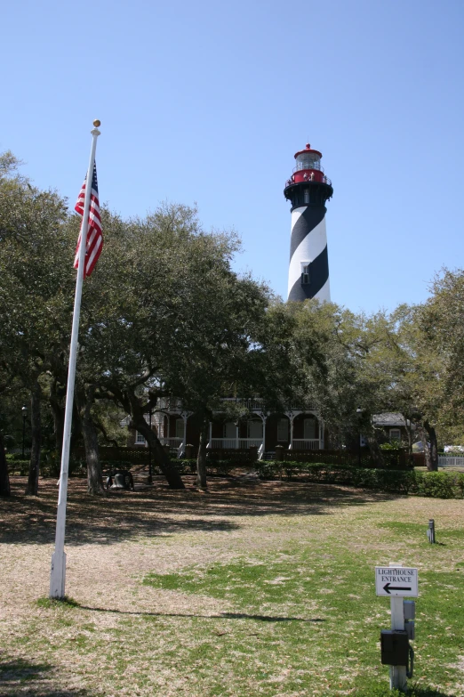 an american flag is in the foreground with a light house in the background