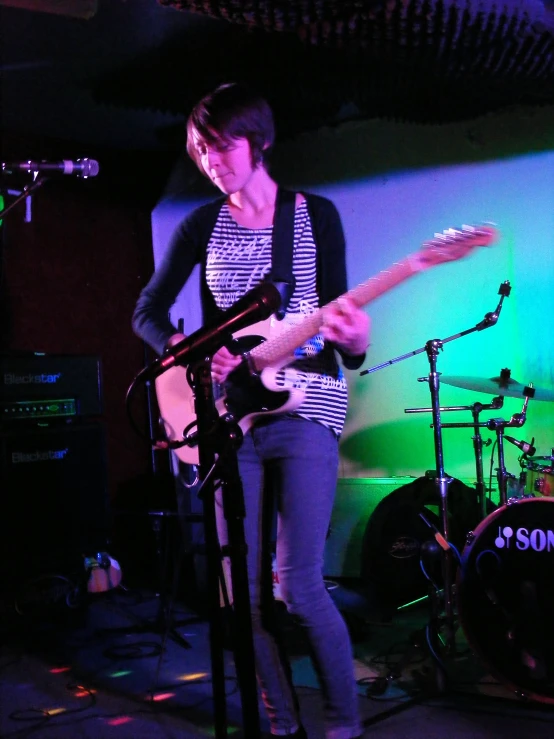 a woman plays guitar in front of a microphone