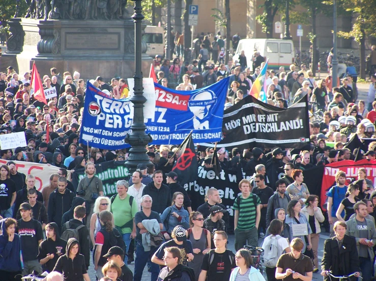 many people with signs are walking in the street