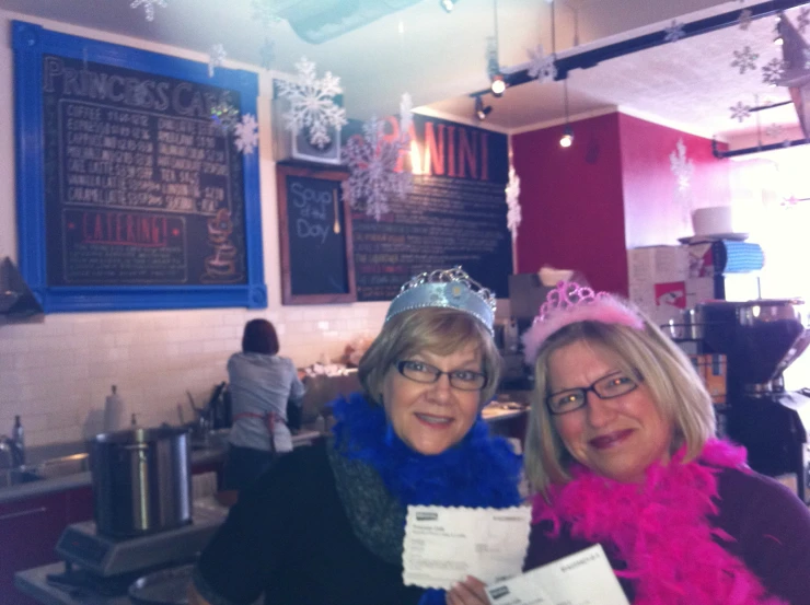 two women pose for a po in front of a menu