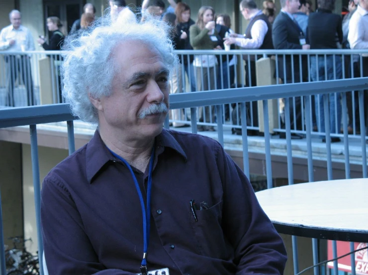 an old man sitting at a table with a mustache on