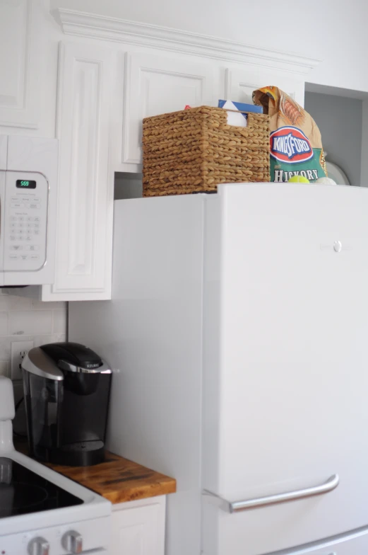 this kitchen has a toaster, coffee maker and bread bin on the refrigerator