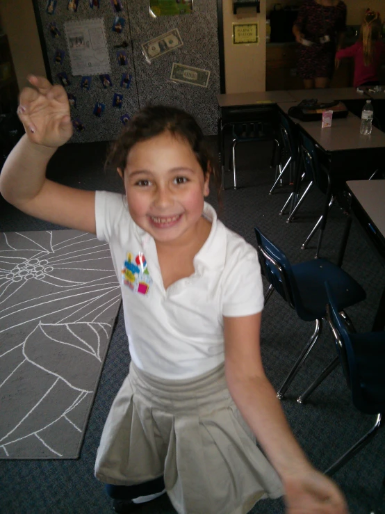 the girl smiles brightly as she sits in a classroom