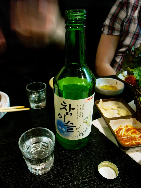 some bottles, chopsticks and bowls sit on a table