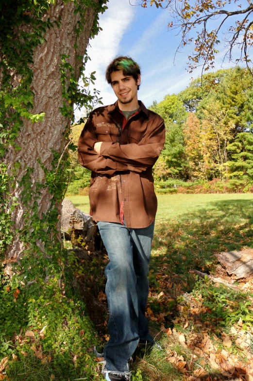 a man leaning against a tree in the fall