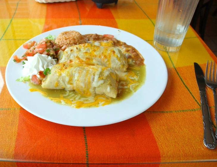 an enchilada dish of mexican food served on a white plate