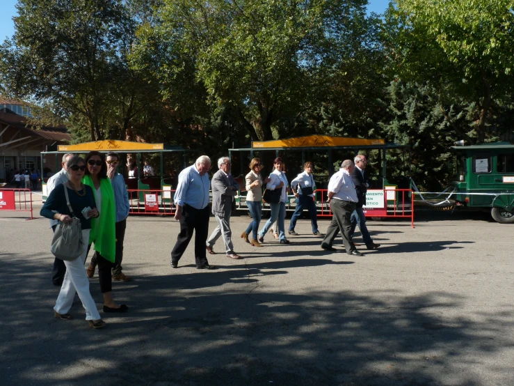 people walking together on a street next to train cars