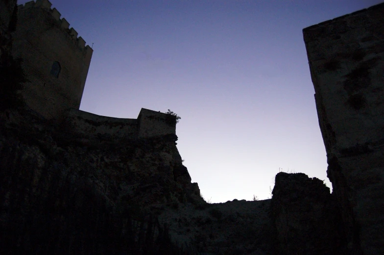 the silhouette of two towers in a dark castle setting