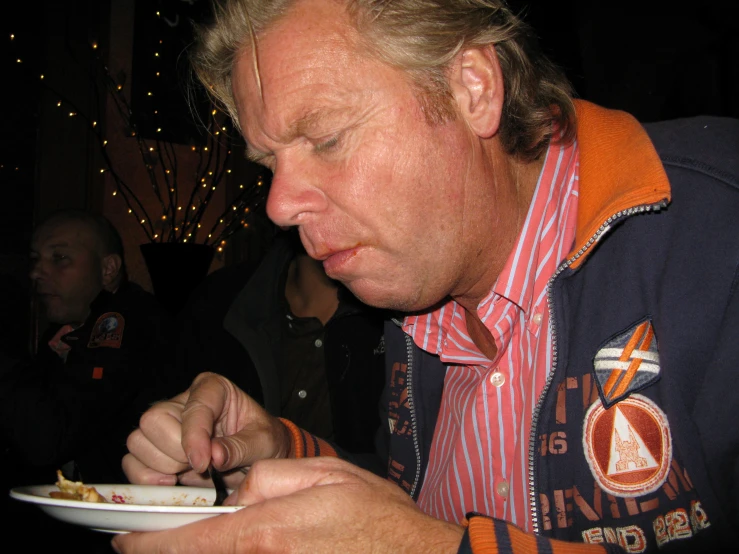 a man holding a plate and eating from it