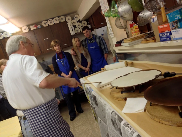 several people in kitchen area with various things on counters