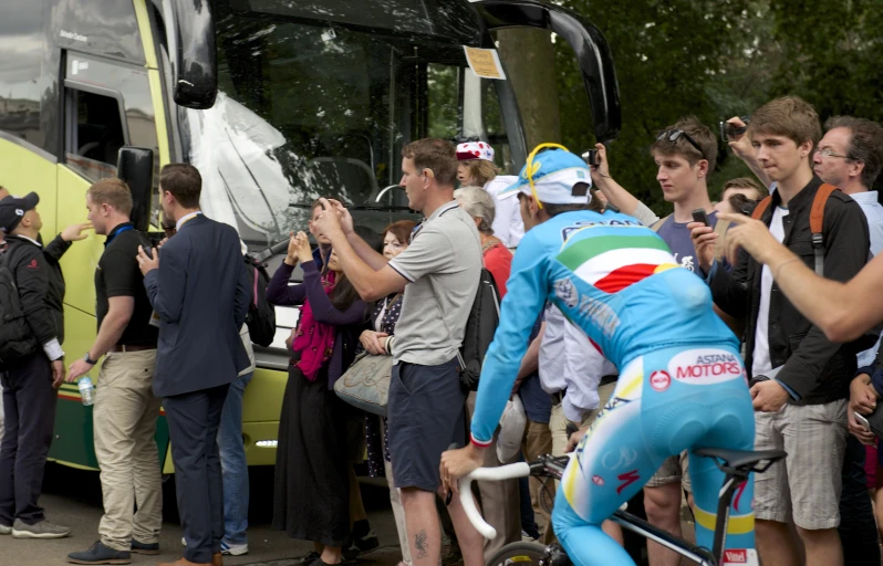 a group of people wearing bibs and cycling helmets looking at the front of a bus