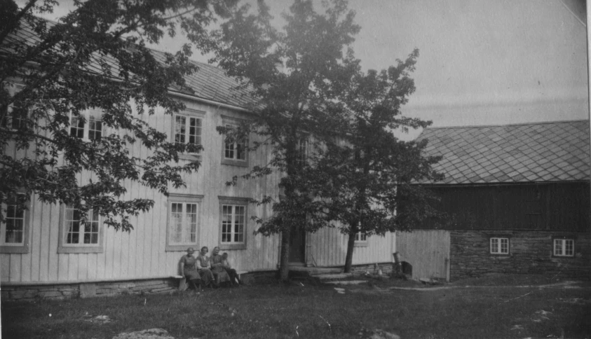 people are sitting under a tree outside of a building