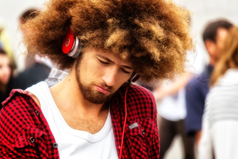 man with afro hair listening to headphones in public