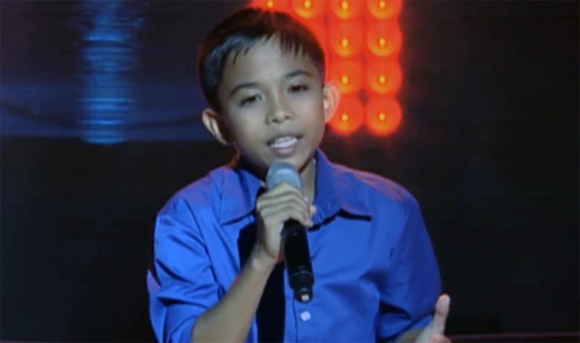 a young man in a blue shirt holding a microphone