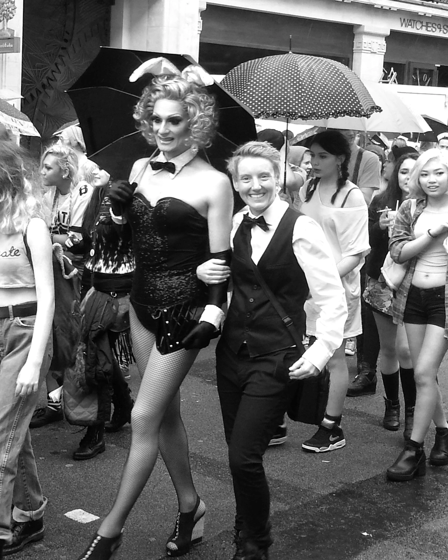 men and women dressed in drag type outfits walk down a crowded street