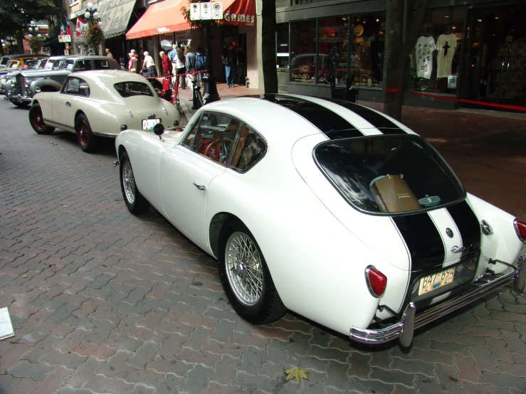 an old vintage car parked near a brick sidewalk