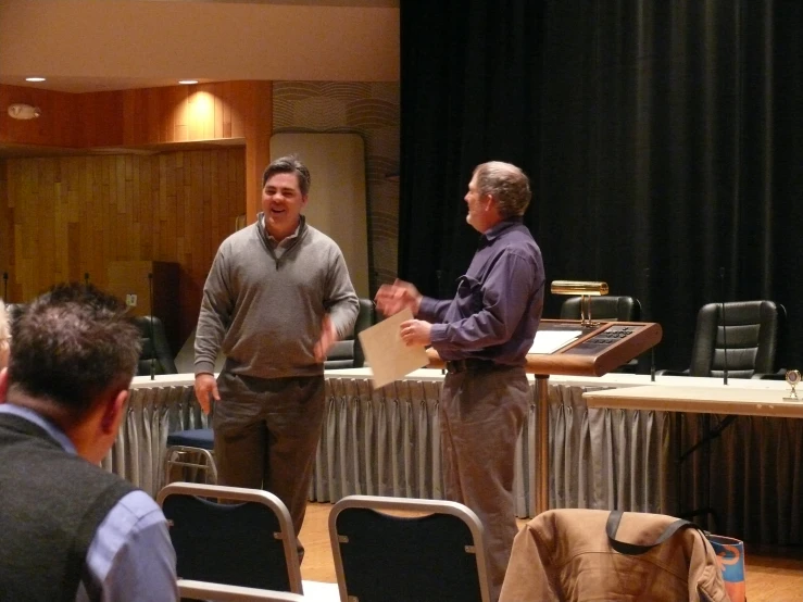 two men standing near each other in front of a stage