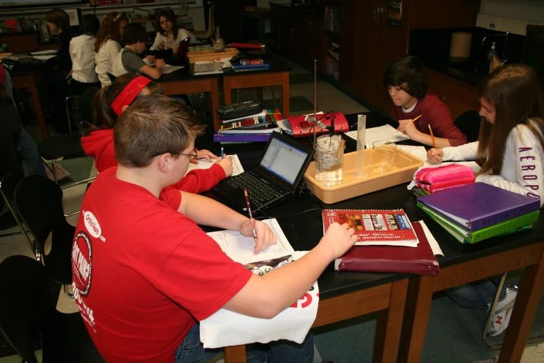 two young people are sitting at a table with books