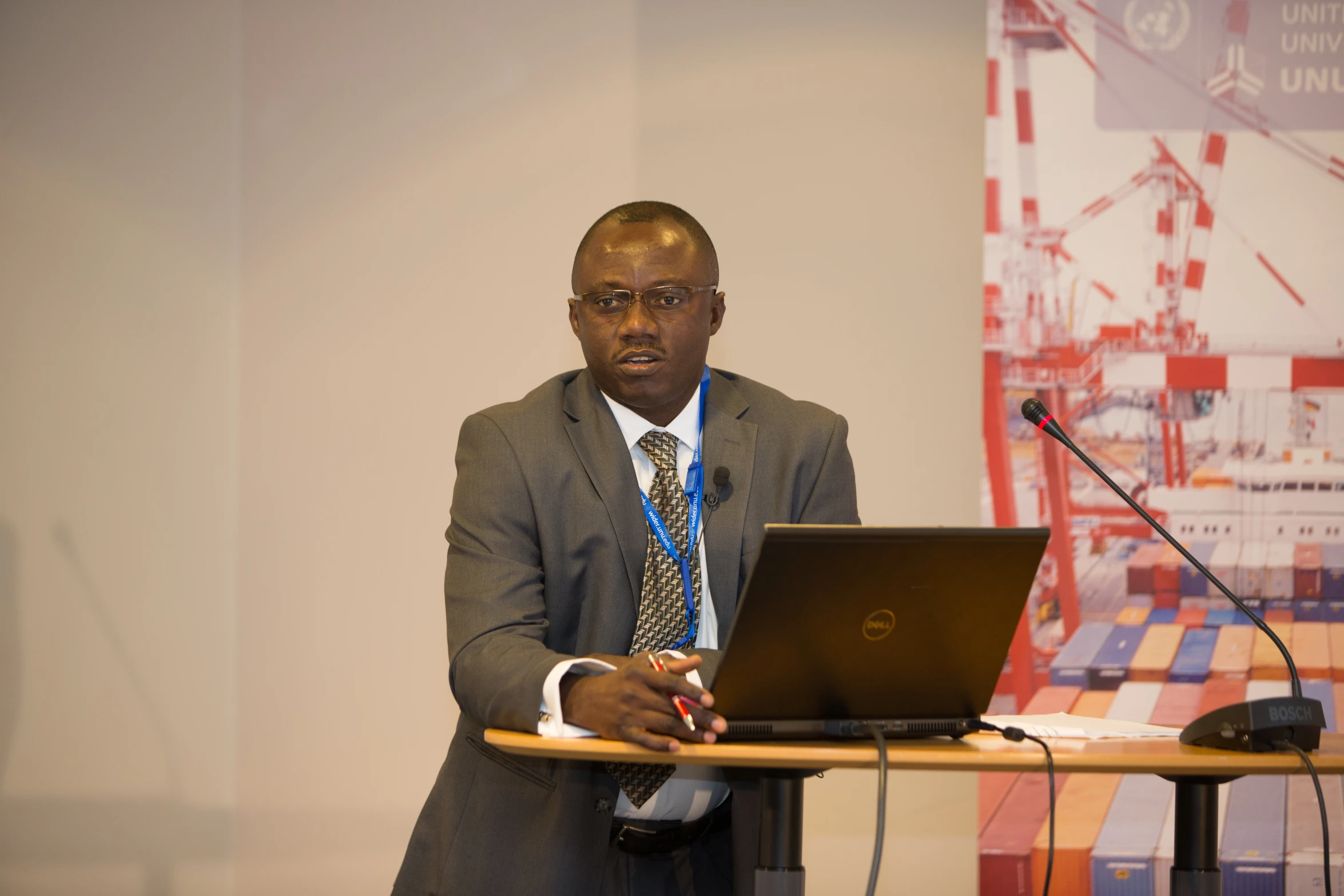 man in grey suit and tie at a table using a laptop