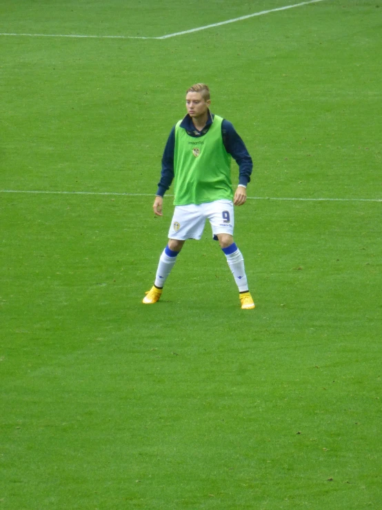the man is dressed in a green and blue shirt and yellow boots