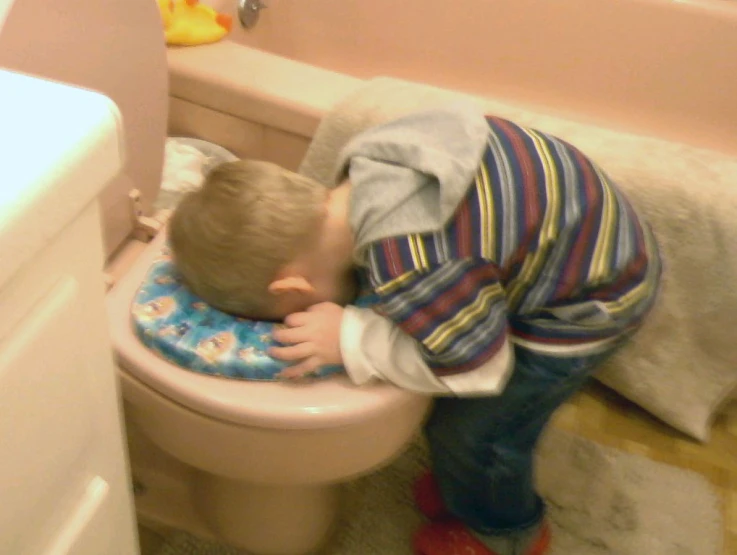 a toddler is playing with the toilet in the bathroom