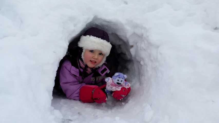 a small child sits in a snow cave