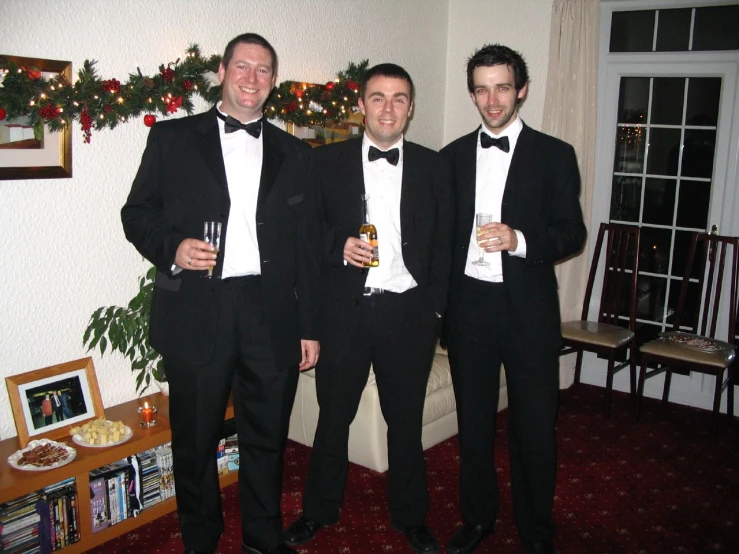 three men in tuxedos pose for the camera
