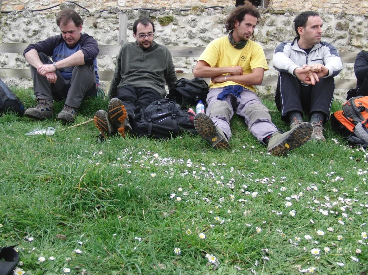 men are sitting in the grass with their hands together