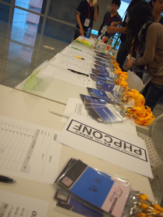 people stand at a long table that has several books and calculators